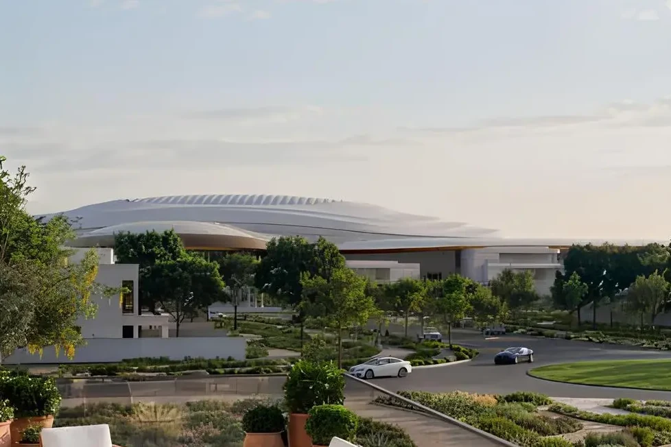The arena's curved roofline seen across the landscaped parkland at Wadeem Gardens